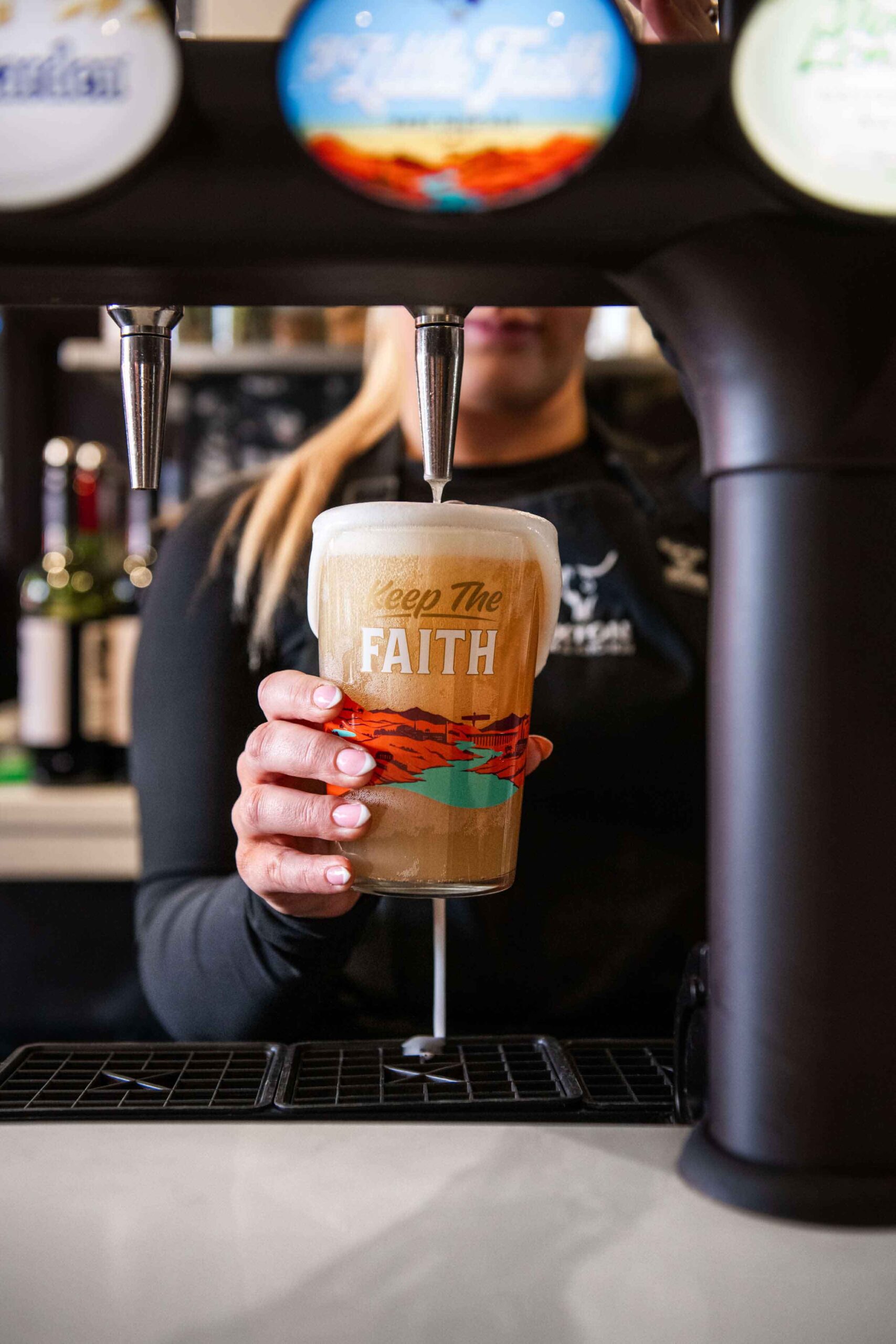 A bartender pouring Keep The Faith Ale from draft tap
